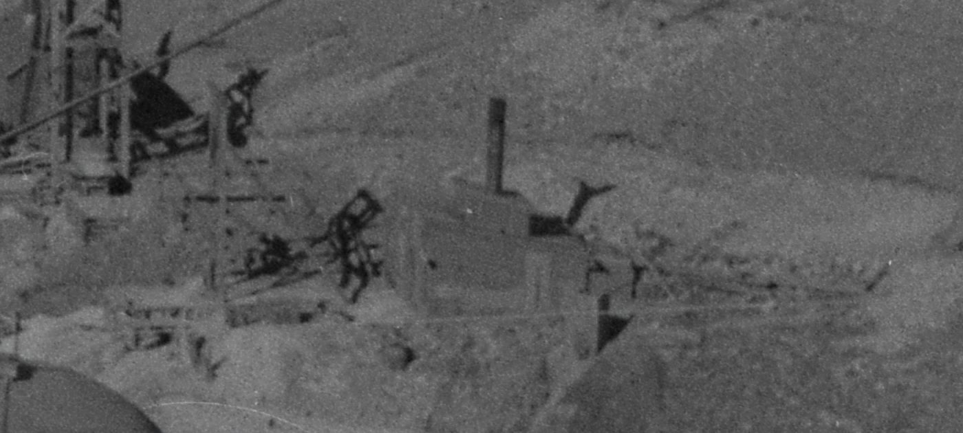View is a negative type of Photo taken by a camera of an older type of Photograph, with not the best quality film so it is rather grainy sadly. Cropped from a view of the Trolley car named Grace climbing Gold Hill high above Poverty Gulch, along the original steep High Line grade, part of the back trolley pole is seen coming in from near upper left-hand corner poking into the image towards right.
* The Granite Hill Mine is seen center with its Hoist House and Head-Frame to the left of it, while in upper left-hand corner is seen part of the head-frame on the May Queen mine.