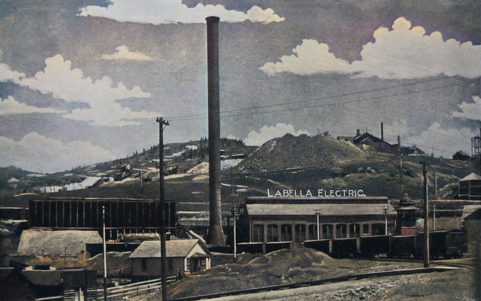 Being the image source is of print type, and I took a quick grab through a compact digital camera, the quality is not the best, but it is what it is! I have worked with it as best as I could. The main focus of this view is the La Bella Electric Power Plant in the foreground. It was located in Goldfield, with Bull Cliff, and Bull Hill at far left, as background, in addition to several mines. The railroad cars seen is on the 3-foot narrow gauge Golden Circle railroad.
   I did procure the colored version of this image as I think it is nicer. Source is gray-toned, or in common speech black & white. Used an online service and tweaked and worked with image to get what looks best to my eyes for the moment.
