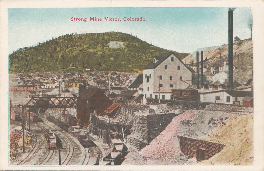This I always felt was a good view of the Strong Mine in Victor, Colorado. The quality of the painted image is not that great, but you get the feel and size from it, how the 3-foot narrow gauge Florence & Cripple Creek yard tracks fits below the ore house and how the standard gauge M.T. tracks pass right in front of the Shaft House of the whitish Strong Mine.