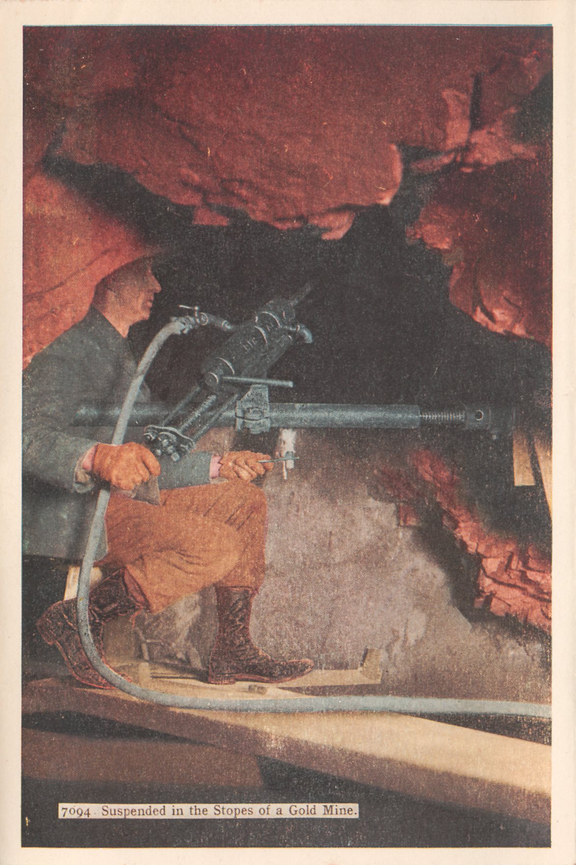 This was one of those 'can be everywhere...' views, but then September 17, 2013, I saw this same view listed on eBay as a postcard view marked as 'Stope in Vindicator Mine, Cripple Creek District.' by Julia Skolas. I also seen the view in a folder marked as being '1800 feet below surface.'
   View is of a miner sitting on some form of a stool, on planks, with a machine-drill suspended unto the walls and he is directing it into the roof area to drill out whatever he must do. He is holding a candle holder with his left hand and the machine with his right hand, and I assume it is more for the look then real working condition.
