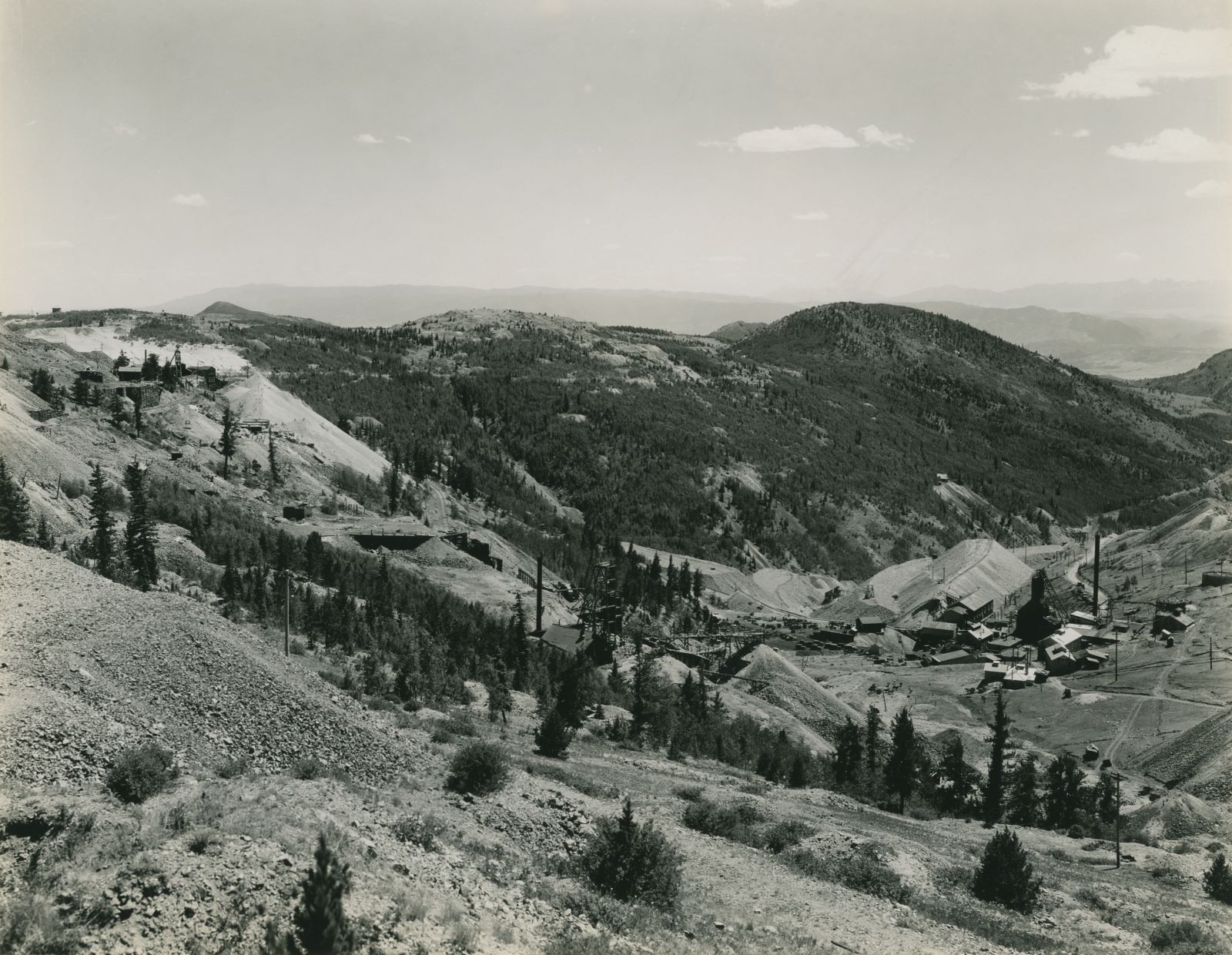 This photo is from the western slope of Bull Hill, looking towards south, southwest near the John A. Logan mine. Down in the valley on the right-hand side of this image is the Cresson Mine, while about center sideways and 1/3 up from bottom is the Head-frame of the Gold Sovereign Mine, with the ruins of the Trilby Mill/Mine further left and a piece of the Gold Sovereign Branch line off the High Line seen climbing the hill below a big dump from one of the Dante Mine shafts seen near left-hand side about 1/3 down from top. The hill seen about 1/3 in from right-hand side is Squaw Mountain, and on the slope down into Eclipse Gulch is seen the mine operation that I think would be the Carbonate Queen. Seen about middle top/down and about 1/4 in from right-hand side.