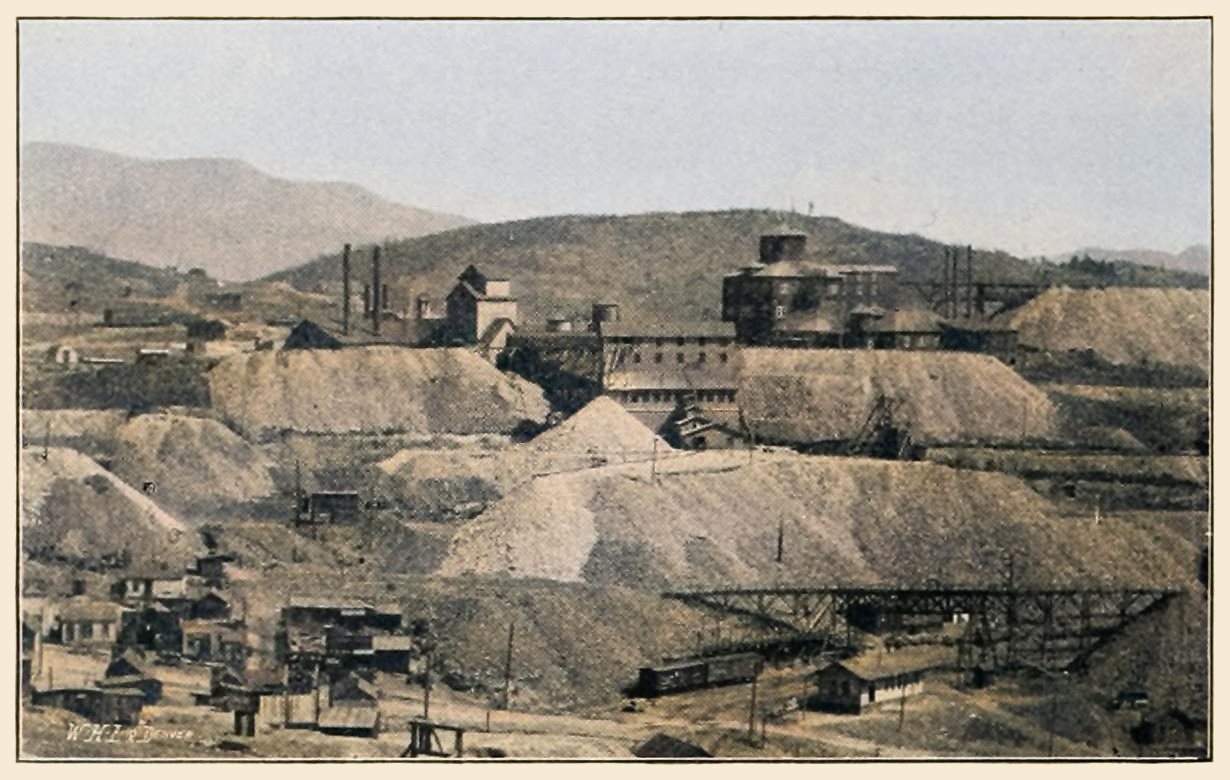 This is sadly a bad quality look due to the print quality and small size, but it shows a view towards the Vindicator No. 1, or main shaft, and the Shaft House and surface structures of the Lillie Mine, seen on the right half side of this view. The Shaft House of the Lillie would when that mine closed be used briefly as an experimental cyanide mill for the Vindicator.
   In the foreground left, lower part of the town of Independence is seen, and on the right the mainline of the Midland Terminal railroad is seen, with its depot.
   I did procure the colored version of this image. Source was grayish, or in common speech black & white. Used an online service and tweaked and worked with image to get what looks best to my eyes at the moment.