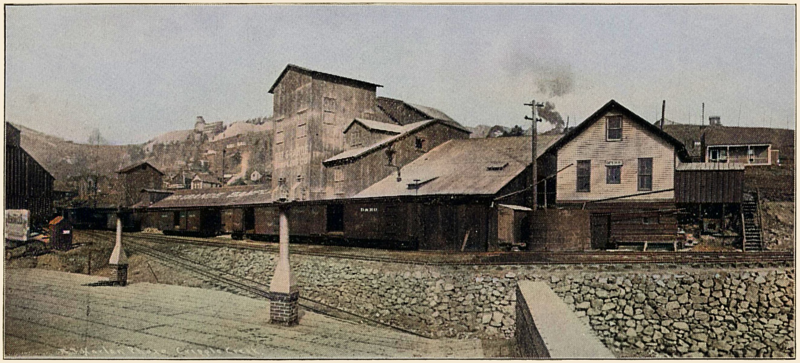 This panoramic view of the Rio Grande Sampler in Victor, by photographer A.J. Harlan, is quite nice to have access to as it tells a little about the lower railroad side of this structure that over the years had different names and owners, from its start as Victor Public Sampler sometime before the railroad came to town. The structures themselves was reported to have been lost in the 1899 Victor Fire so this view here is how it looked after it got rebuilt.
   Direction of this view is in a northwesterly direction, Battle Mountain is in background left, with its transition over to Squaw Mountain at the left-hand side. This Sampler was located just below the Midland Terminal yard in Victor and was served by dual gauge tracks as it served as a switchback entry down to the Strong Ore-house for the M.T. as well as one can see on the foreground dual-track it allowed the F. & C.C. access to the Sampler.
   At the left-hand side, about middle top/down, partly seen, is the Ore-House of the Mary Cashen Mine that was also served by the tracks at this location.
   I did procure the colored version of the image. Source was gray-toned, or in common speech black & white. Used an online service and tweaked and worked with image to get what looks best to my eyes for the moment.