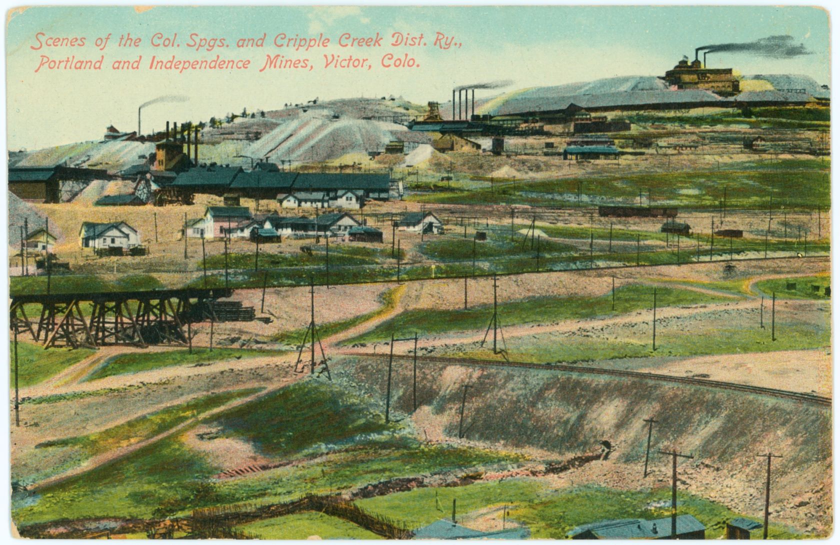 This view by L. C. McClure from 'inside' 'half-loop' of the F. & C.C. entering the southeast slope of Battle Mountain to get to Victor, seems to be from around 1906-1907 as the large Independence Mill has yet to come into existence, but there area several structures that might be the test mill I've seen reported about in that timeframe. Also, it looks like the No. 1 shaft of the Portland mine is now an open Head frame and I've seen reports of all the surface structures of the Portland No. 1 burning in May 1906, dating this view to be after that timeframe.
   In the foreground the fill on the roadbed for the 3-foot gauge Florence & Cripple Creek railroad is seen, passing under the trestle bringing the High Line and the Short Line standard gauge track into Victor outside the view at left. The roadbed of the Golden Circle railroad is partly visible about middle top/down of this view, and then the Stratton's Independence Mine is seen taking up about half width on the left part of this view, while the Ajax Mine is seen with its single smokestack poking up against the sky on the left background.
   The Portland Nos. 1 & 2 make up the right half background part of this view, the no. 2 shaft being the upper one, with the long dumps out from each side of the mine structures.