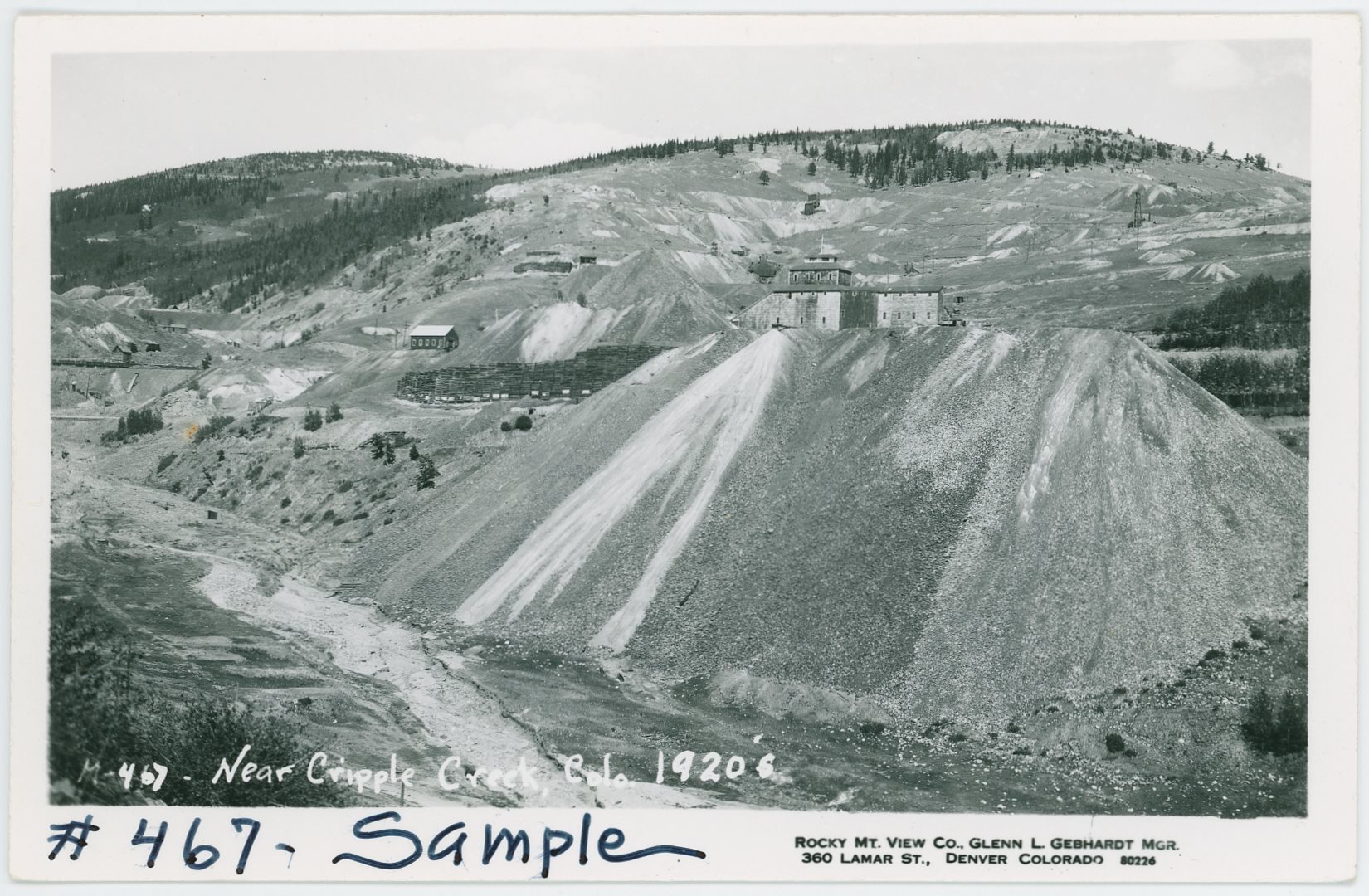 A view in Squaw Gulch towards the huge dump of the Mary McKinney Mine who's structure is popping up behind the dump, against the backdrop of Raven Hill with still a couple of mine ruins standing here and there. Image is marked to be from the 1920's, and in lower left it is still visible some flat parts, like terraces, from structures in the former town of Anaconda.